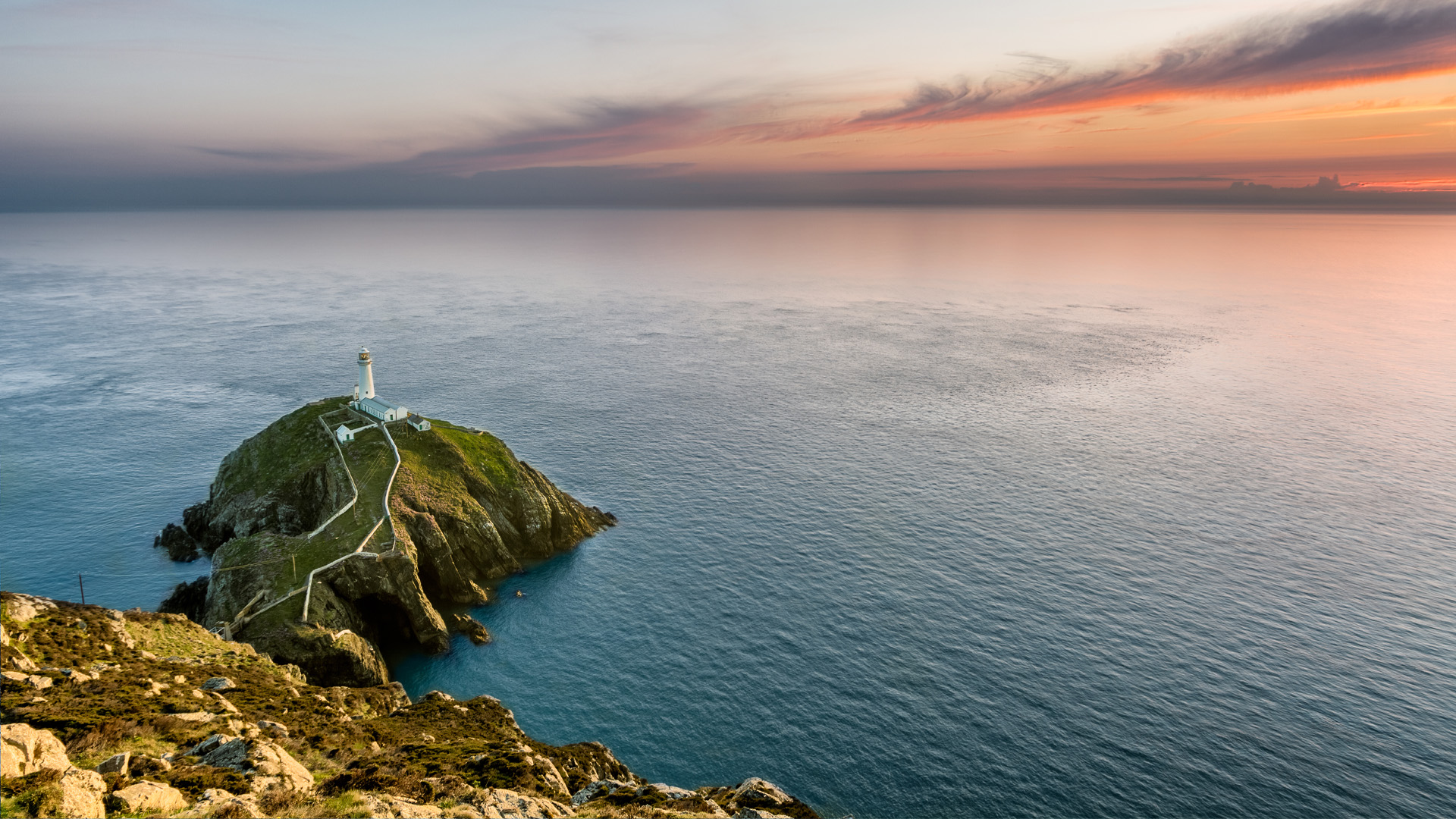 A view of a lighthouse and the sea from a cliffside