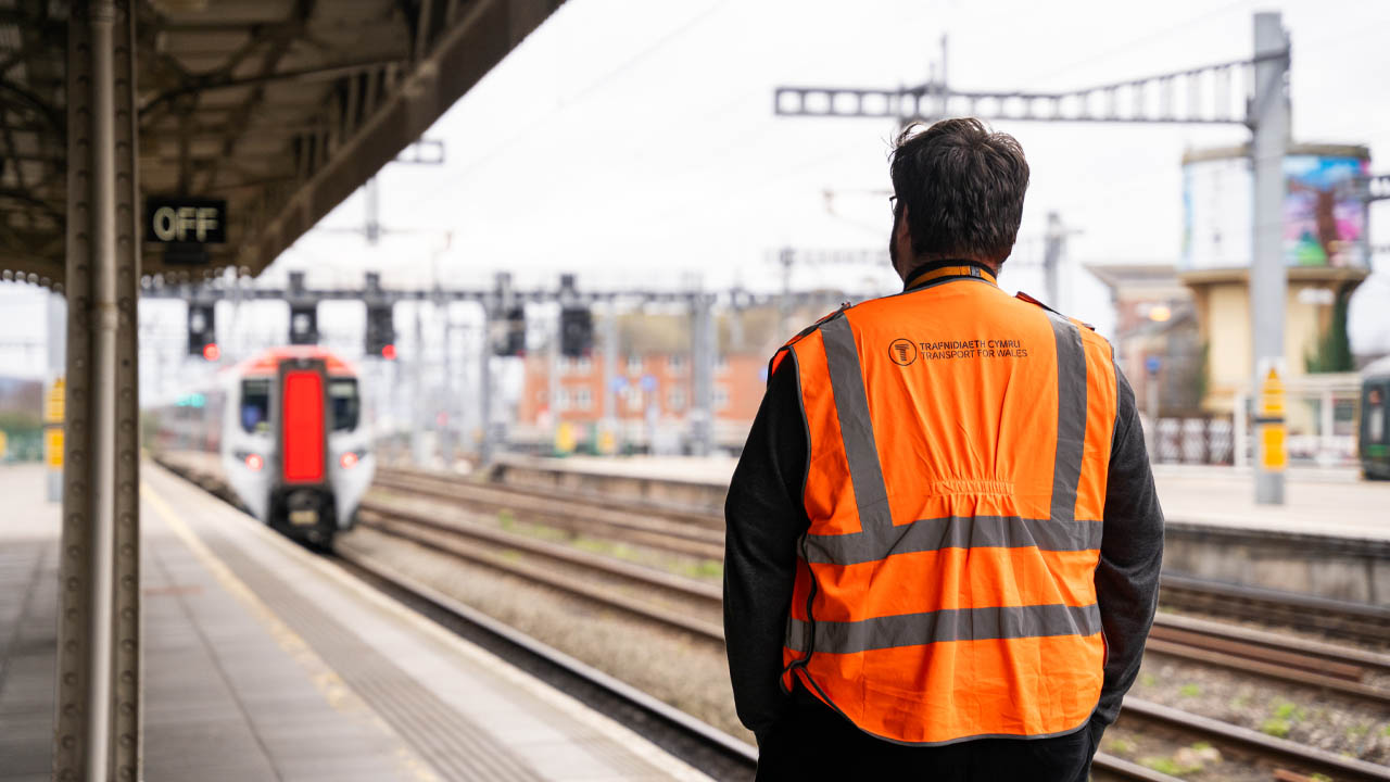 Aelod o staff sy'n gwylio trên yn gadael y platfform | Staff member watching a train depart from the platform