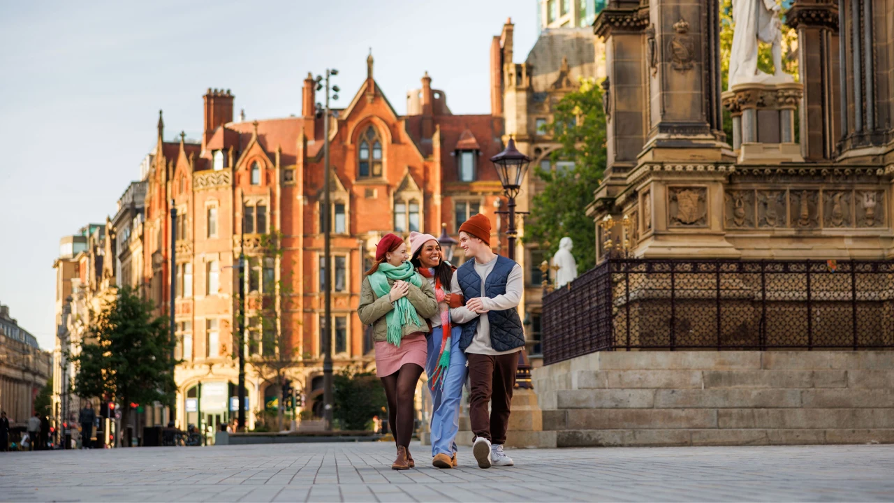 Three people walking through Manchester